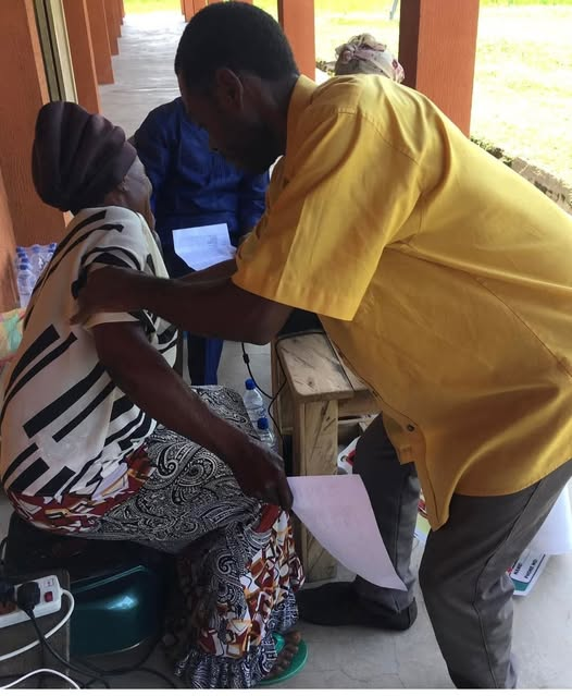 Staff member assisting an older person during a health screening