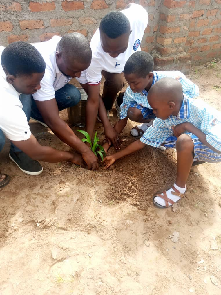 Students and staff planting a tree together
